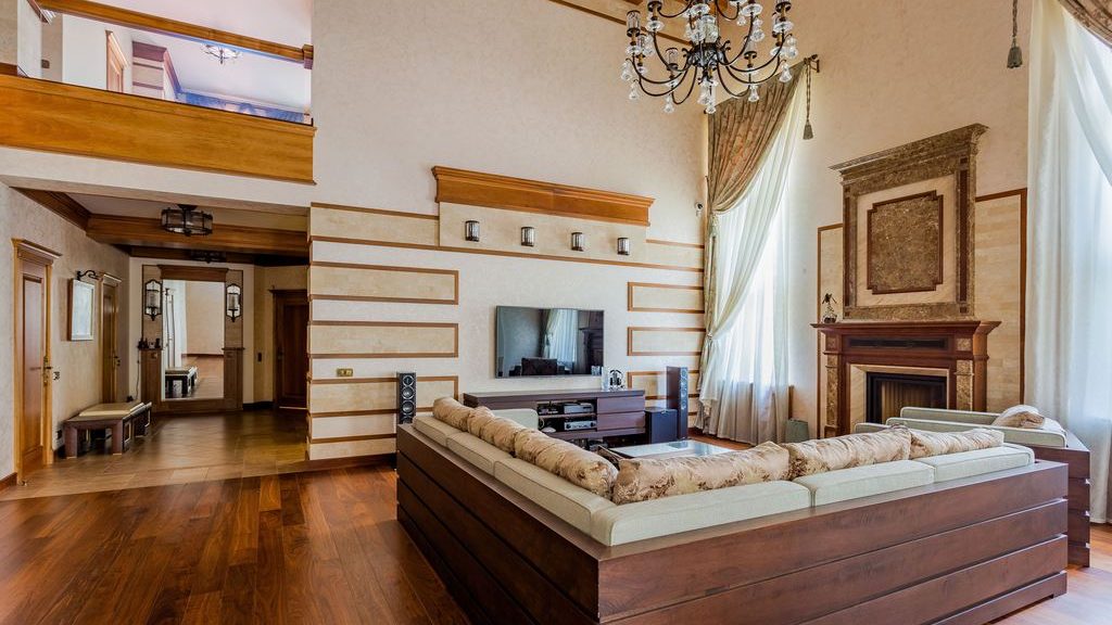 Large square living room with a low sectional sofa, TV wall, fireplace, and a separate open pathway beside the seating area.