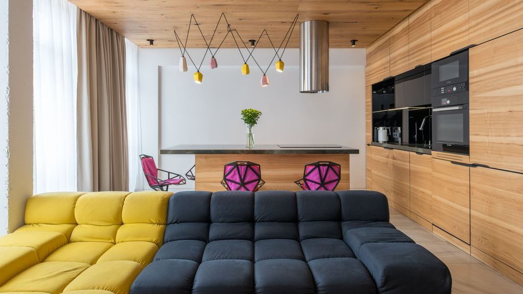 sofas in different colors side by side near a rectangular with a marble top and several purple chairs in an open-plan room