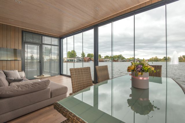 Lakefront living room with floor-to-ceiling windows, low-profile seating, and open water views that create a relaxed, nature-connected retreat.