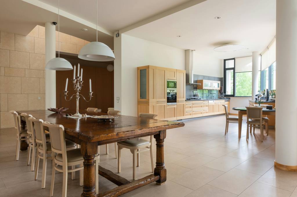a long rectangular wood dining table with chairs in a dining room next to a living room with wood furniture