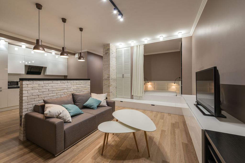 Small apartment living room with compact sofa, nesting coffee tables, TV console, and open kitchen arranged for efficient everyday living.