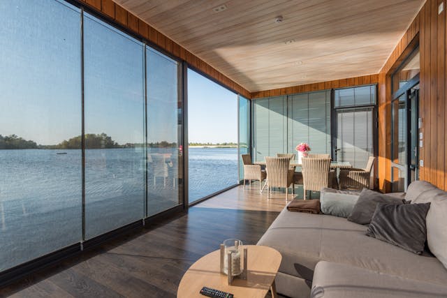 Contemporary living room with glass doors opening toward water.