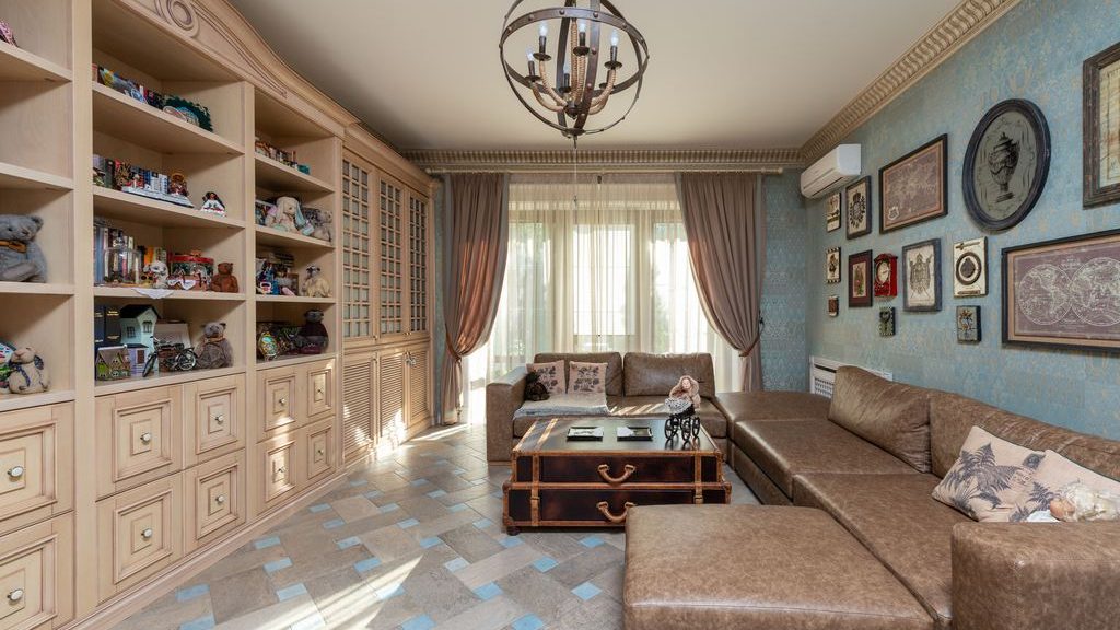 Cozy family room with a brown sectional, built-in storage cabinets, open display shelves, and a trunk-style coffee table.