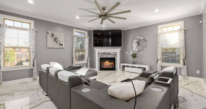 Gray power reclining sectional with cup holders facing a fireplace and wall-mounted TV in a bright modern living room
