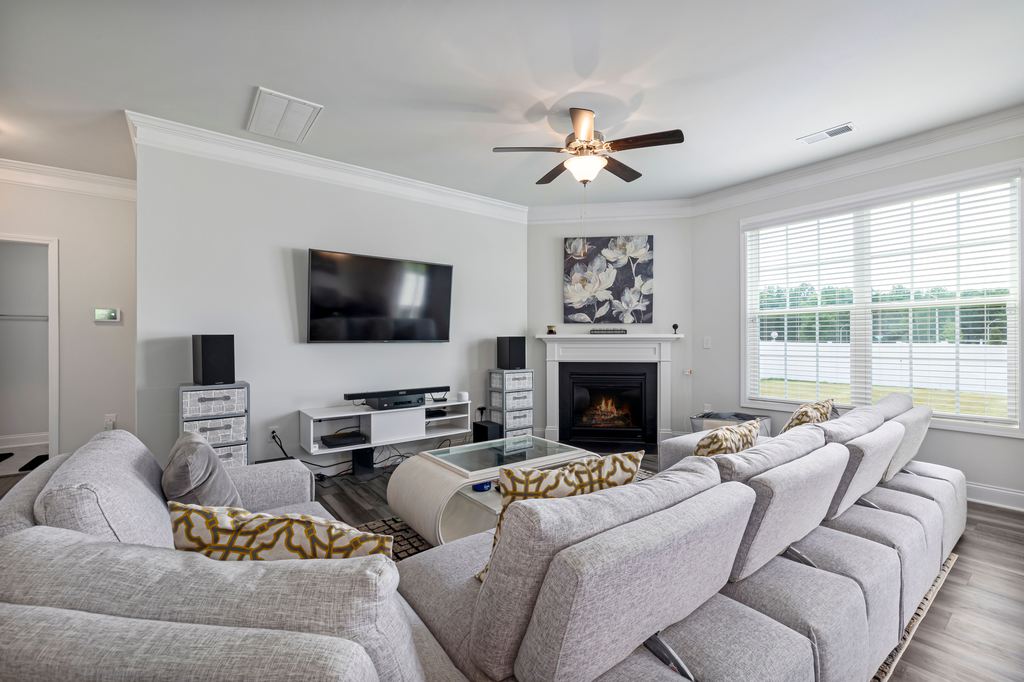 Bright living room with gray reclining sectional seating facing a wall-mounted TV and fireplace.