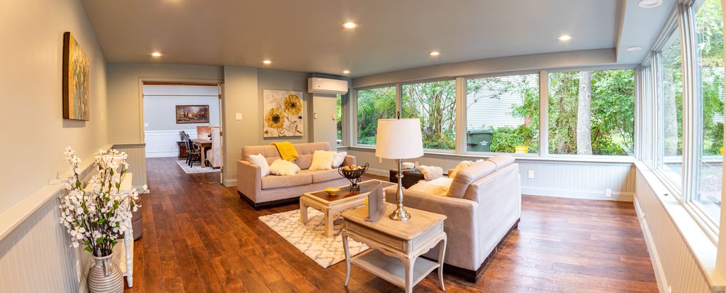 two grey sofas near a wood side table, a wood console table and a rectangular low wood coffee table in a bright and large living room