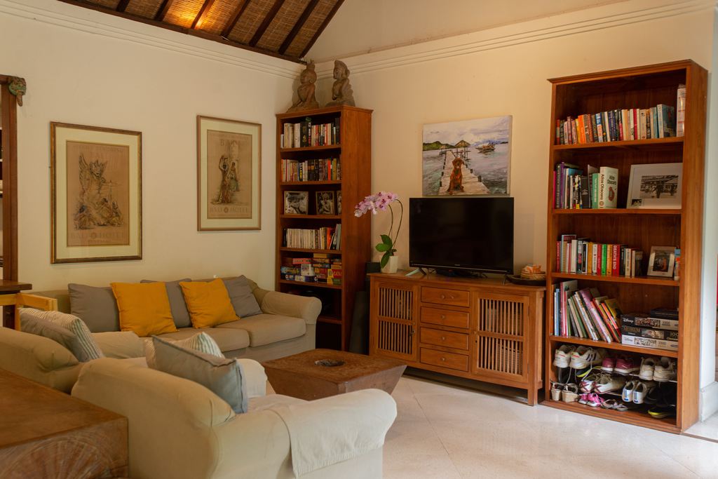 Cozy living room with wood bookcases, a TV console, beige seating, and books arranged around the media wall.