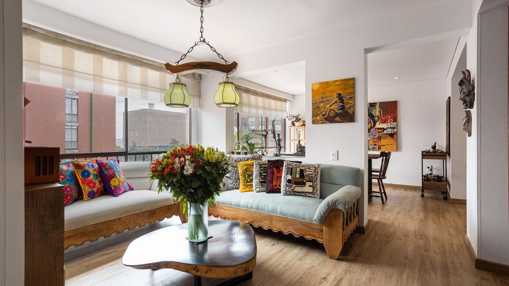 two sofas in same size and style but different colors in an L shape layout near a wood coffee table with a flower on top in a cozy and bright apartment