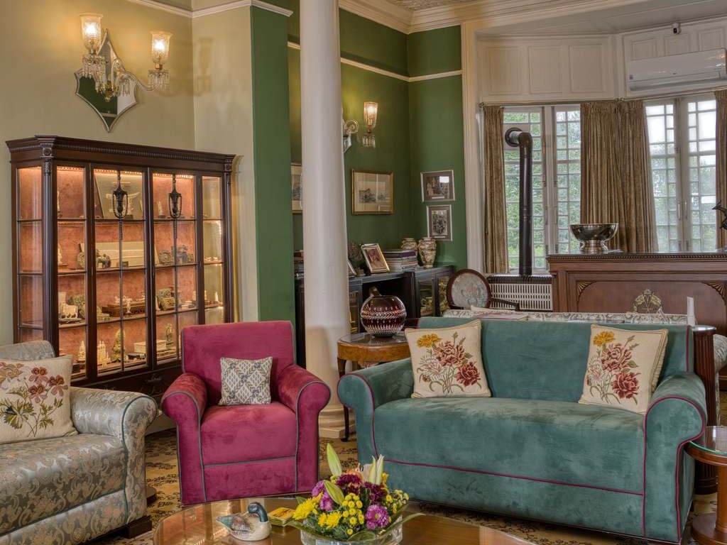 a blue and a grey sofa with a pink accent chair in the middle near a wood side table, a wood coffee table and a storage cabinet in a mid century living room
