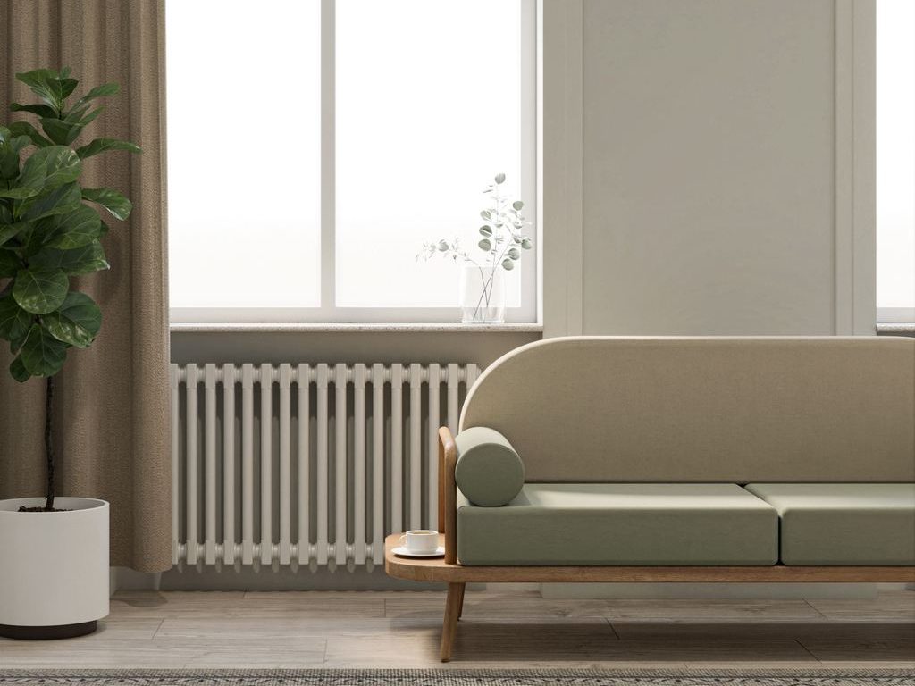 Minimalist living room with arched windows, soft green sofa, beige curtains, indoor plant, patterned rug, and natural wood accents.