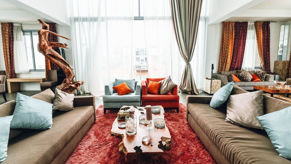 two same sofas with cushions facing toward each other with a wood coffee table in the middle near two accent chairs in different colors