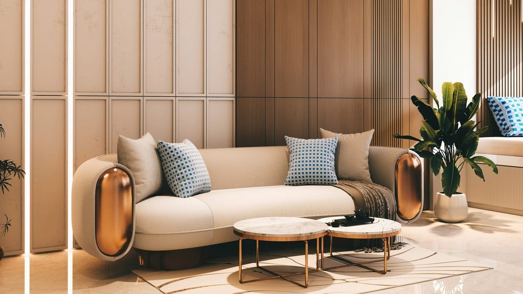 Modern living room with a cream sofa, bronze curved armrests, nested marble coffee tables, vertical wood paneling, and a potted plant.