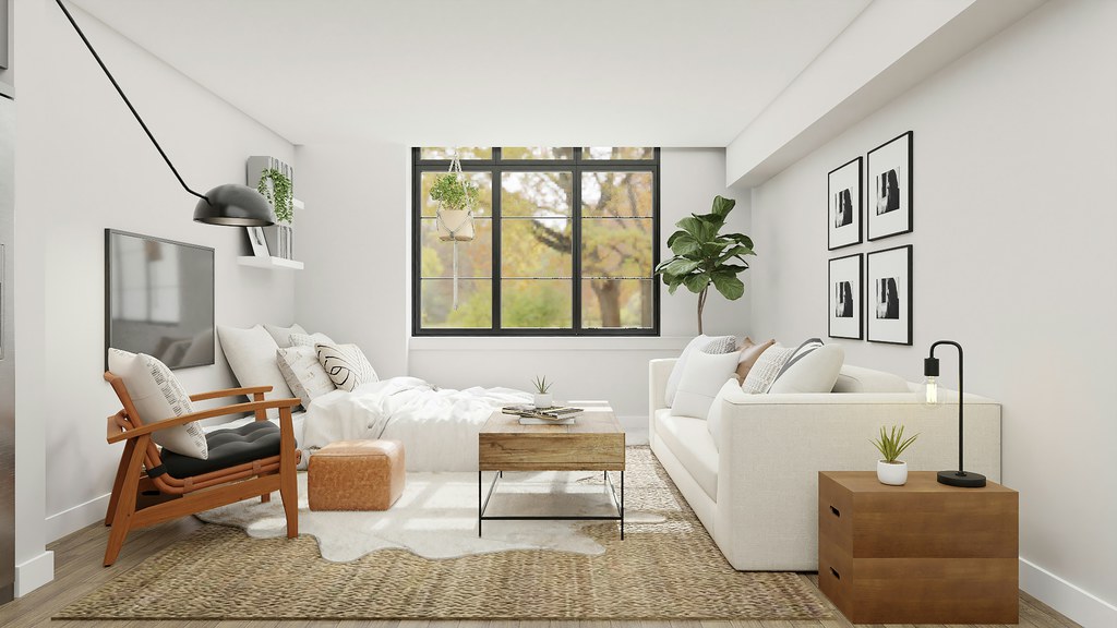 Compact modern living room with a daybed placed beneath a black-framed window, white sofa, wooden accent chair, coffee table, and neutral decor.
