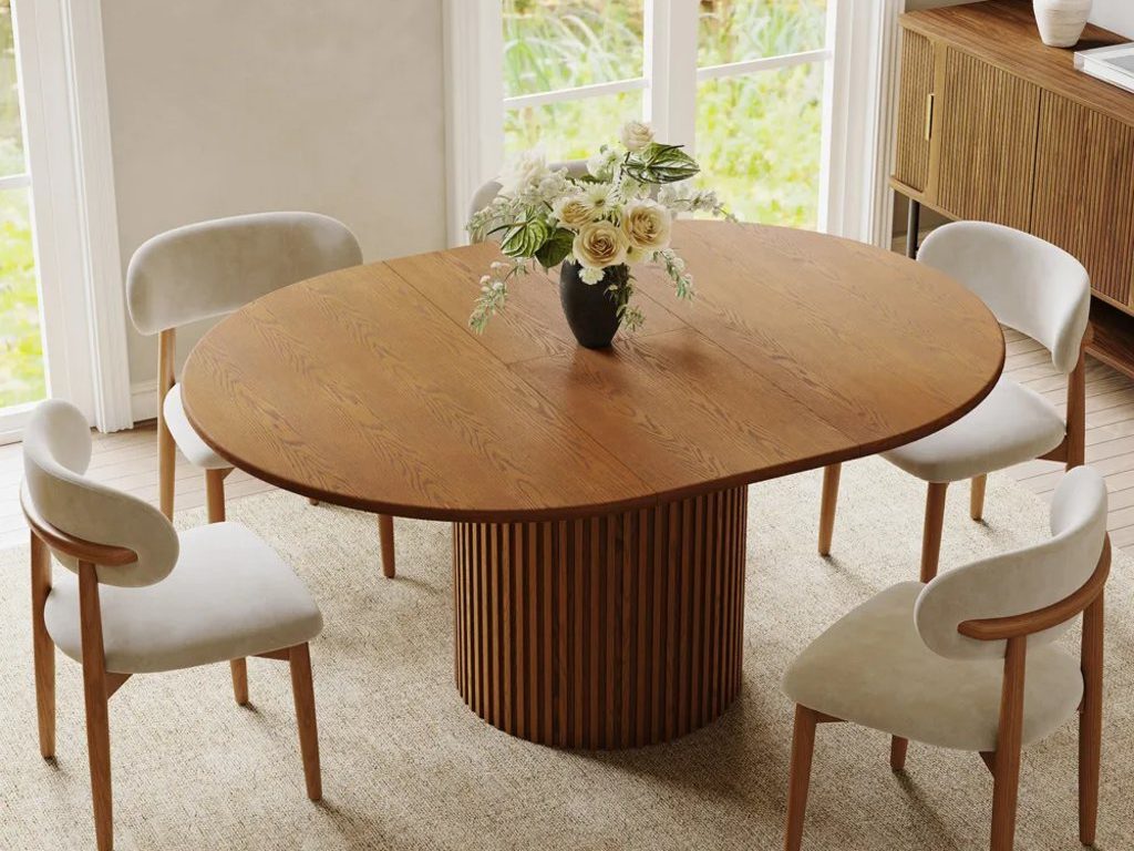  Silva-Round Extendable Dining Table with four dining chairs and a flower on top near a wood tufted cabinet in a modern traditional dining room