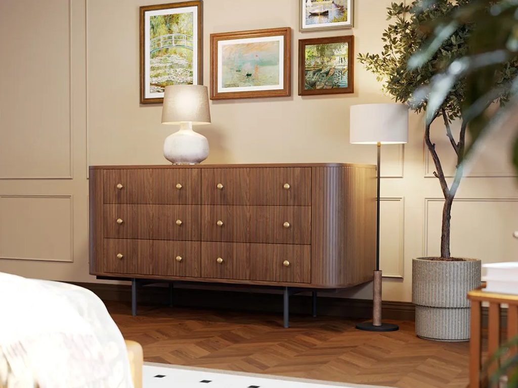 Modern traditional bedroom with warm wood dresser, framed wall art, soft lighting, paneled walls, herringbone wood floor, and neutral decor.