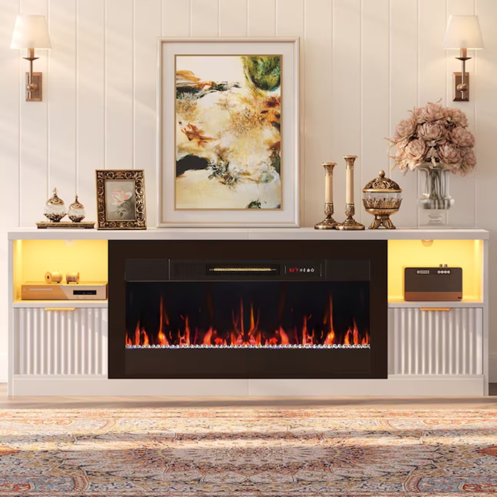 Bestier White Fluted Fireplace TV Stand with drawers and storage for a radio and a console, some candles, a flower, a painting and some decorations on top in a modern living room