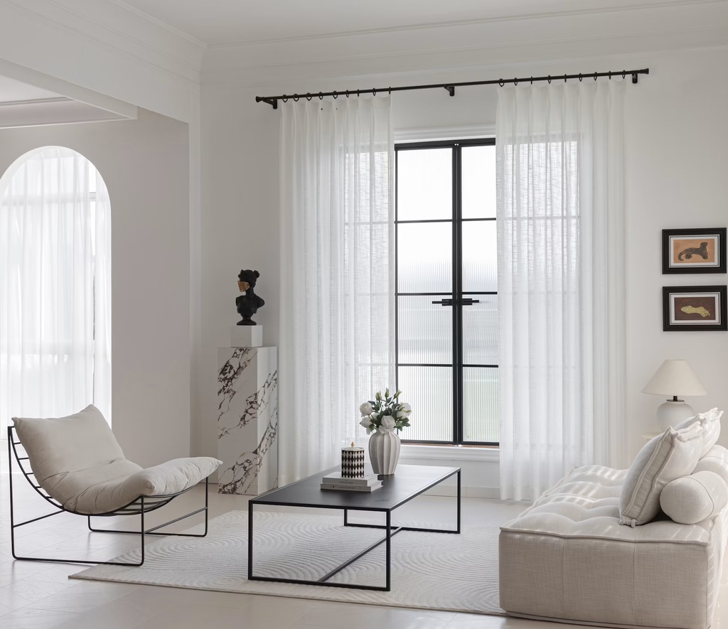 a minimalist living room with a white accent chair, a rectangular coffee table and a sofa beside a lamp
