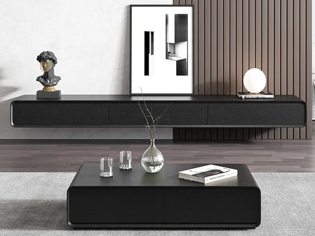 a black floating media console with a book, a lamp, a statue and a painting on top near a rectangular black coffee table in a minimalist living room