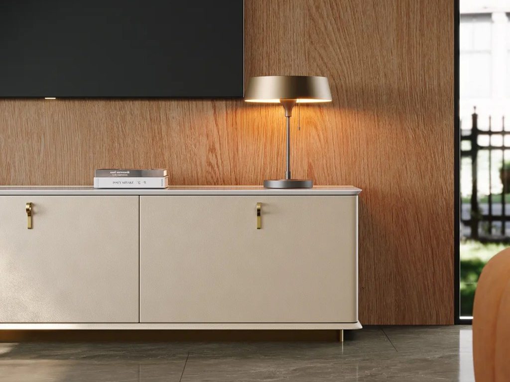 Modern transitional media wall with a cream storage console, wood panel backdrop, table lamp, neutral rug, and wall-mounted TV.