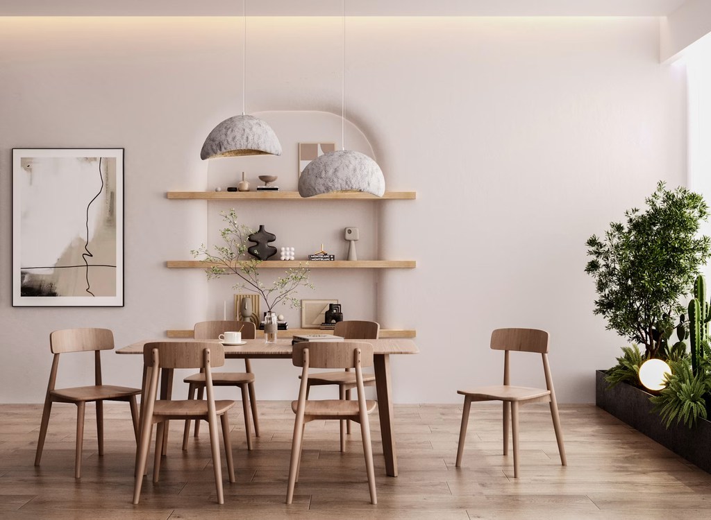 Light wood dining table and chairs in a minimalist modern dining room with floating shelves, pendant lights, and indoor plants.