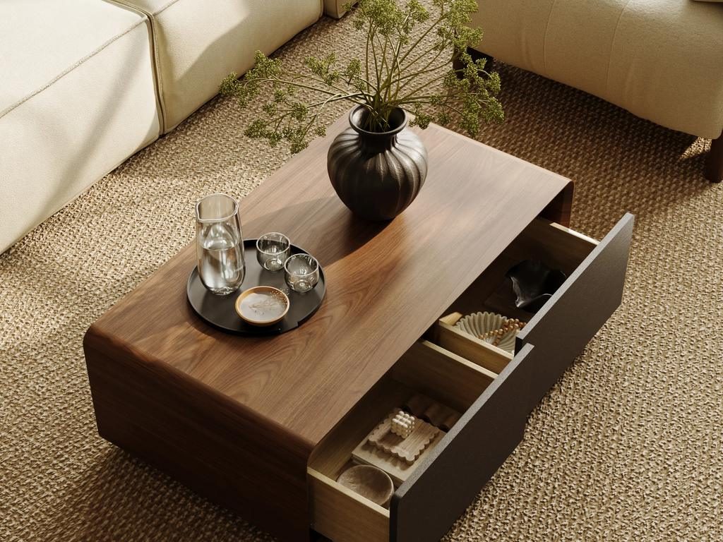 A warm wood coffee table with a black round tray, glassware, and vase decor in a neutral living room with hidden storage.