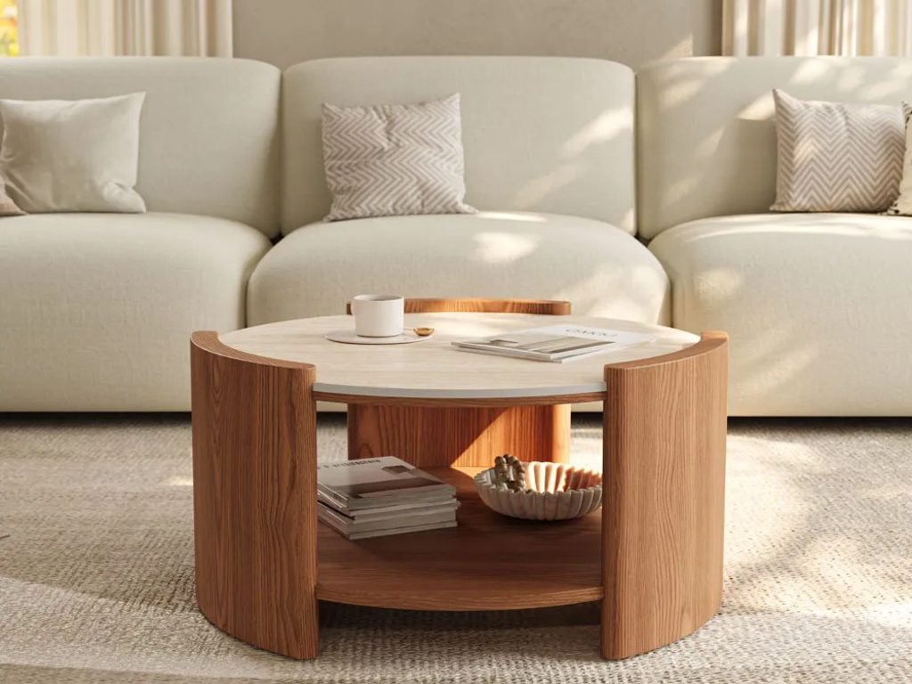 Round coffee table with a light stone top, warm wood storage shelf, and simple decor in a neutral living room.