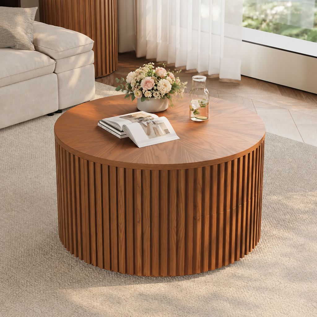 Low floral arrangement in a ceramic vase on a round walnut coffee table with an open book and glass carafe in a bright modern living room.