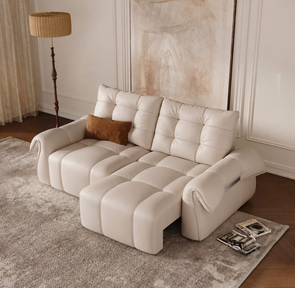 Cream reclining sofa with an extended footrest in a warm neutral living room with a floor lamp and abstract wall art.