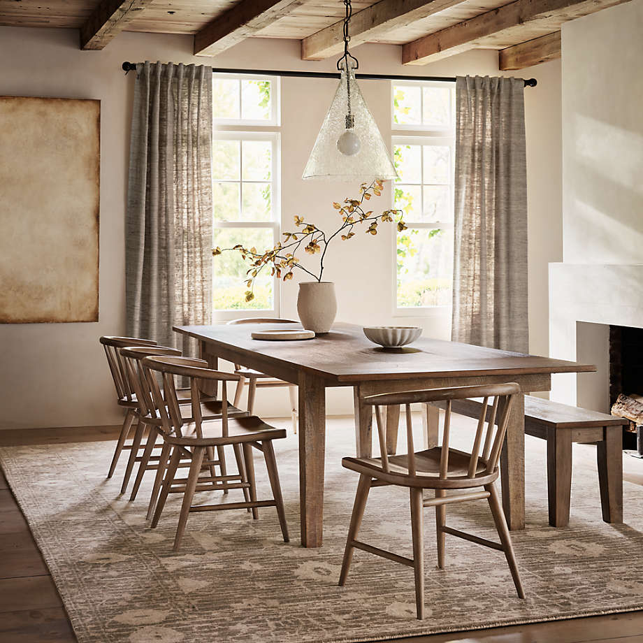 Large rectangular wooden dining table with four chairs and a bench in a rustic dining room.