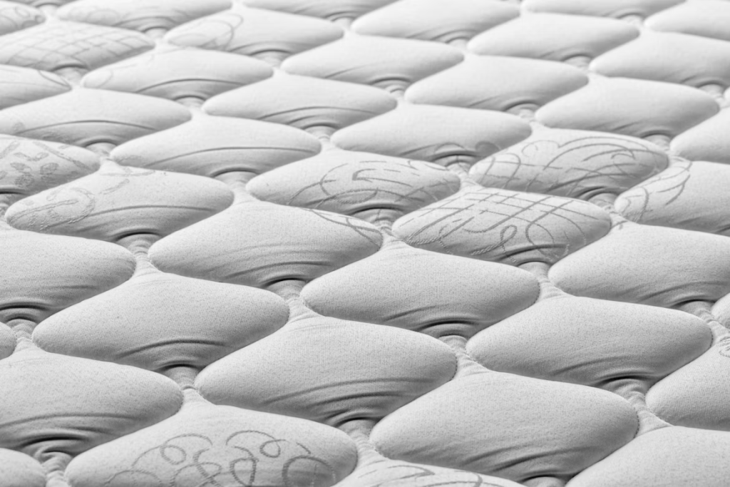 Macro shot of a tufted mattress surface, showing fabric indentation and sagging depth for quality wear measurement.