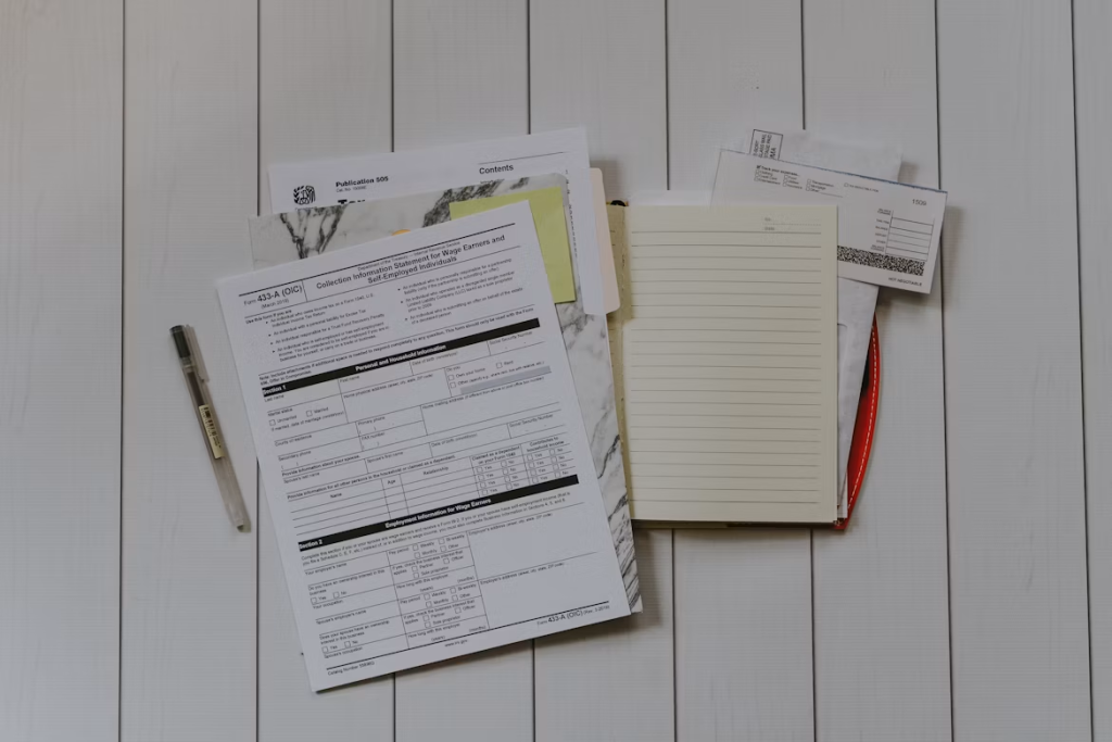 A paper checklist laying on a white wooden desk alongside a notebook and pen for daily task tracking.
