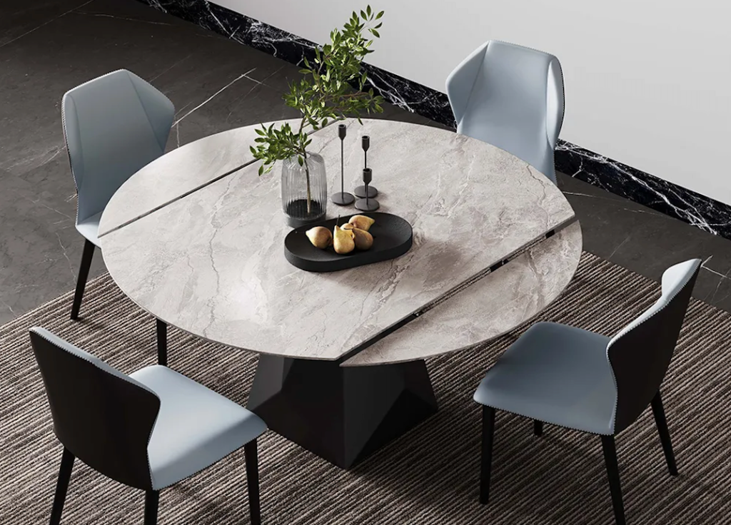 Overhead view of a round faux-marble dining table with pull-out leaf extension panel and pale blue leather chairs.