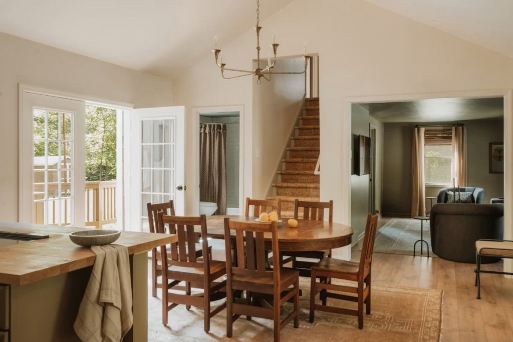 Classic dark wood oval dining table and matching chairs styled in a warm rustic home near a staircase.