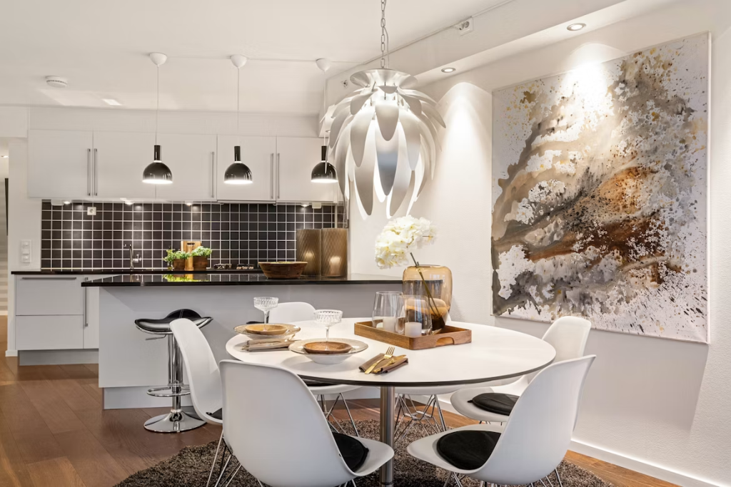 Modern white circular dining table with sleek white chairs in an open kitchen layout, styled with warm lighting.