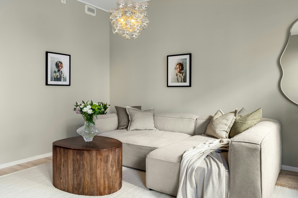 Round wood coffee table in front of a beige sectional sofa in a neutral living room