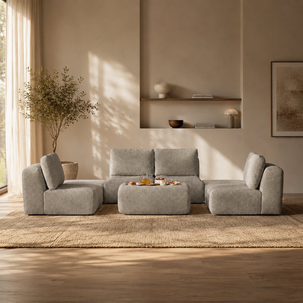 Gray modular sofa with a matching upholstered ottoman used as a coffee table in a warm modern living room.