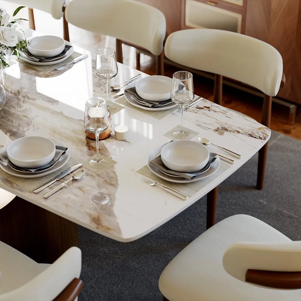 Glossy stone dining table set with white dinnerware, wine glasses, and cream upholstered chairs.