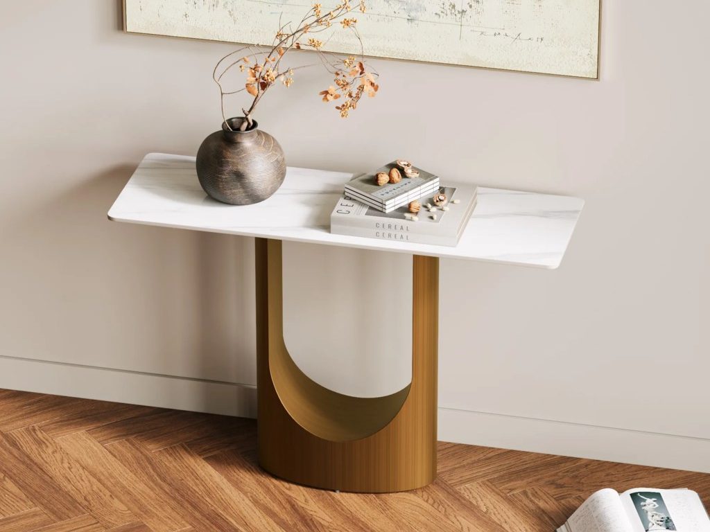Dark textured vase with dried branches on a white console table, styled with books beneath abstract wall art.