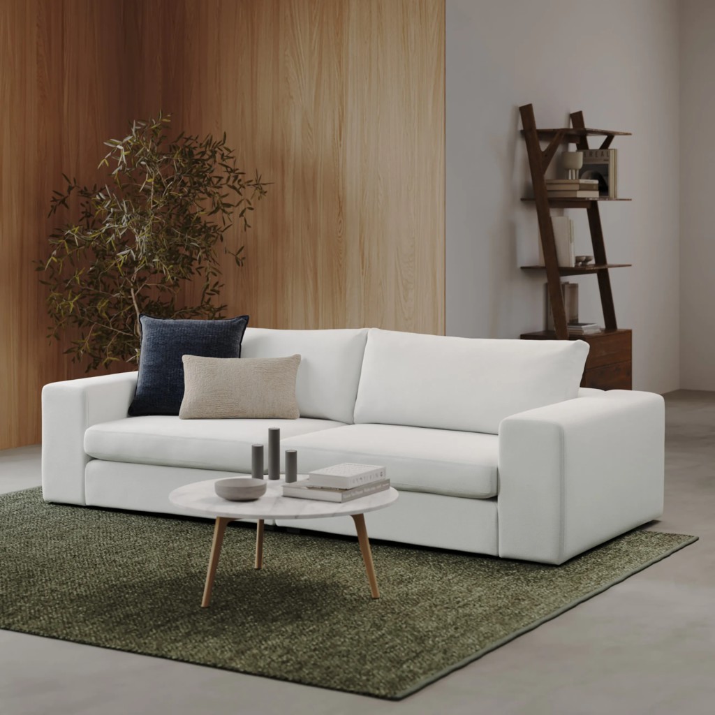 White three-seat sofa with wide arms and accent pillows in a modern living room