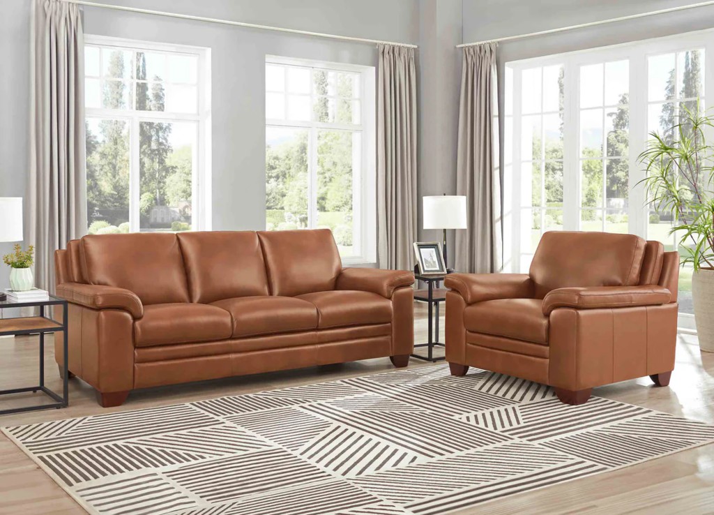 Chestnut brown leather sofa and matching armchair arranged in a bright living room with large windows and a geometric rug