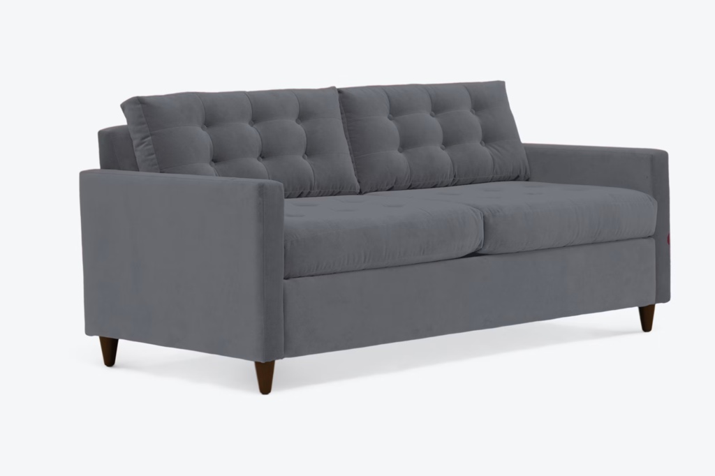 Dark gray tufted sleeper sofa with loose back cushions on a white background.
