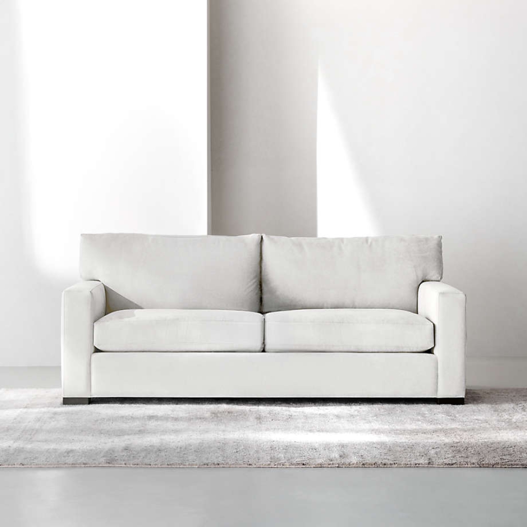 White queen sleeper sofa with two seat cushions in a minimalist Airbnb living room