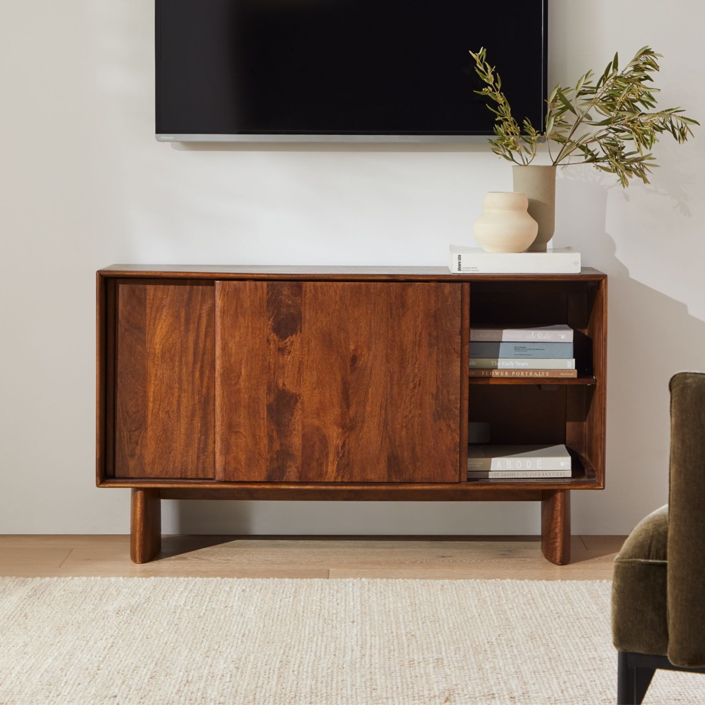 Walnut narrow TV stand with sliding doors and open shelves beneath a wall-mounted TV.