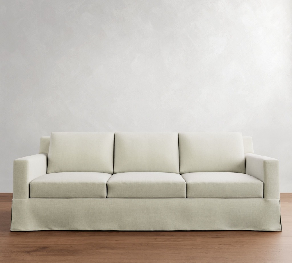 Cream slipcovered three-seat sofa against a white wall in a clean, minimalist Airbnb living room