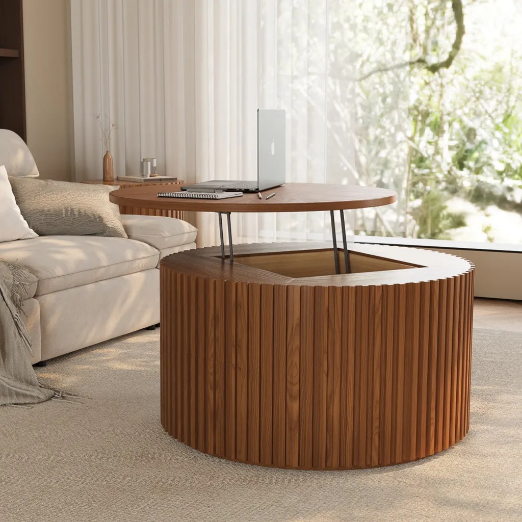 Walnut lift-top round coffee table with a fluted drum base, raised tabletop, and hidden storage beside a cream sofa.