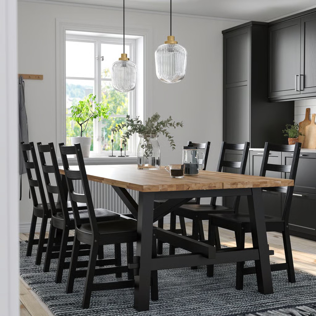 Large rectangular wood dining table with eight black chairs in a modern kitchen dining area.