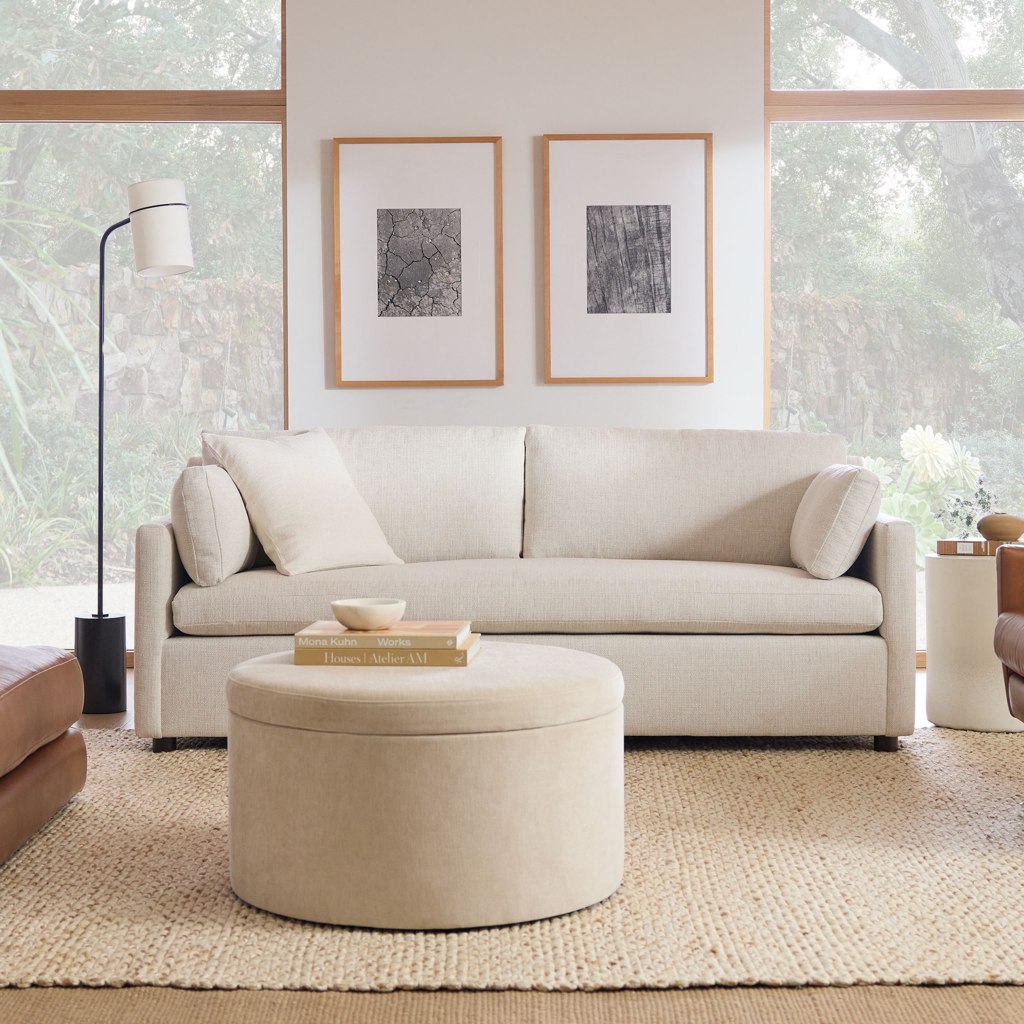 Cream sleeper sofa with loose cushions and bolster pillows in a bright modern living room
