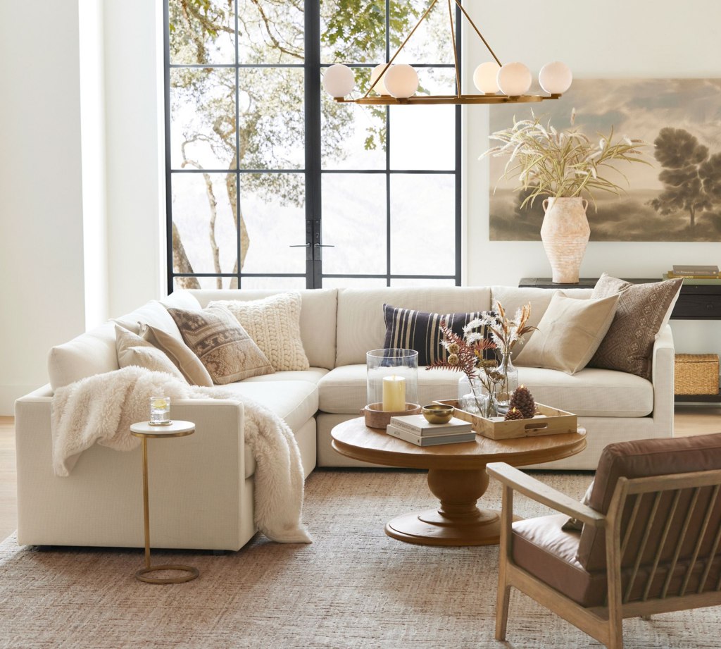 White L-shaped sectional sofa with layered pillows in a bright modern living room.