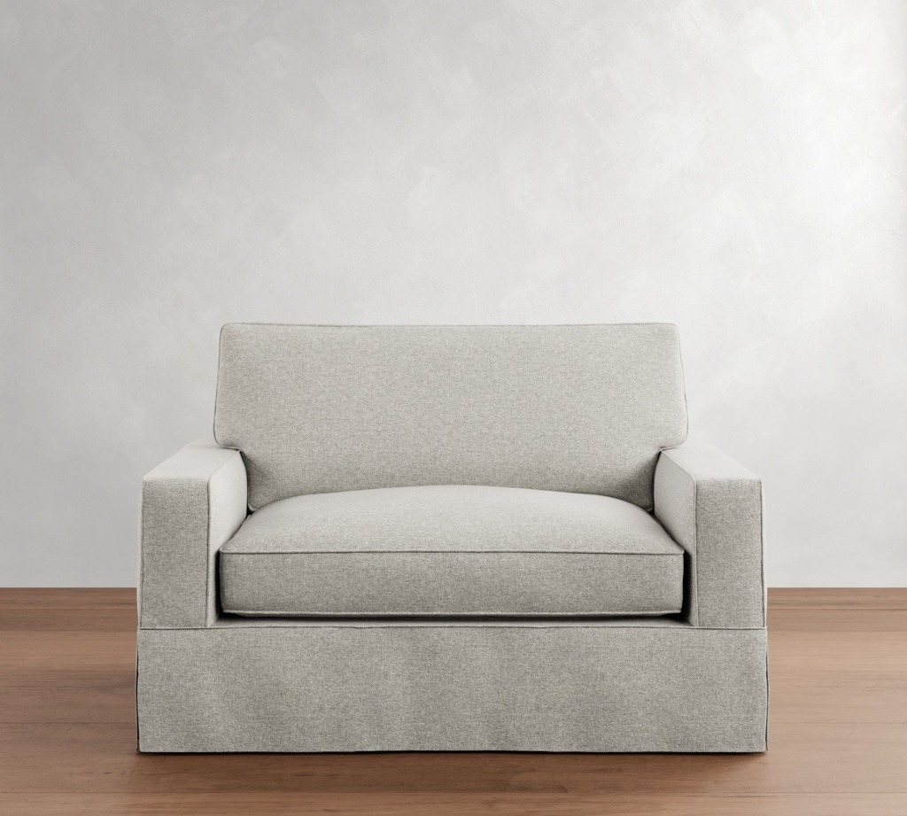 Light gray oversized armchair with a wide seat and boxy arms against a minimalist white wall.