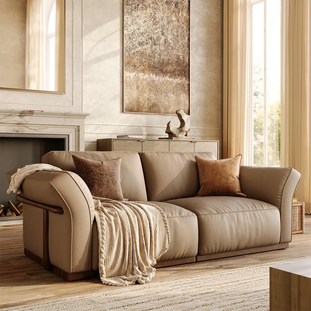 Light beige sofa with brown pillows and a knit throw in a sunlit neutral living room with a fireplace.